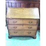 A 19th century oak bureau with inlaid internal secretaire with three long drawers with brass