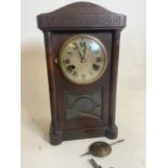 An early 20th century oak mantle clock with pendulum and key with bevelled glass five panel