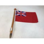 A Naval red ensign ships flag on wooden pole with brass base. Height of pole 64cm W:47cm x H:30cm