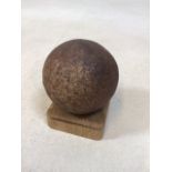 A cannon ball on wooden stand possibly found in Portsmouth harbour H:10cm