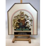 A Plaque - By Appointment to Her Majesty The Queen. Painted moulded plastic figures on board W: