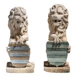 A decorative pair of reconstituted stone seated lion garden sculptures holding a coat of arms, H 69