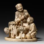 A Japanese ivory Meiji period okimono representing a street vendor and his son, H 12,8 cm - 461 g (+