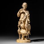 A Japanese Meiji period ivory okimono depicting an old man feeding cranes, H 40,4 cm - 3200 g (+)