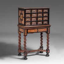 A cabinet-on-stand, ebony and rosewood veneered, the drawers decorated with ivory inlaid grotesques,
