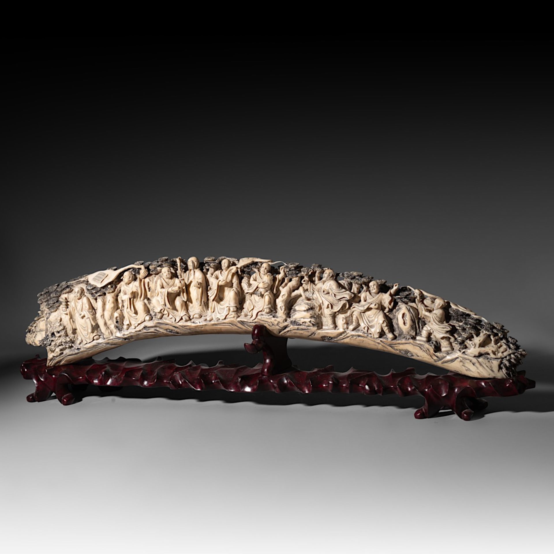 A Chinese late Qing/early Republic carved ivory tusk, on an exotic wooden base, W 85,6 cm - 5700g (+