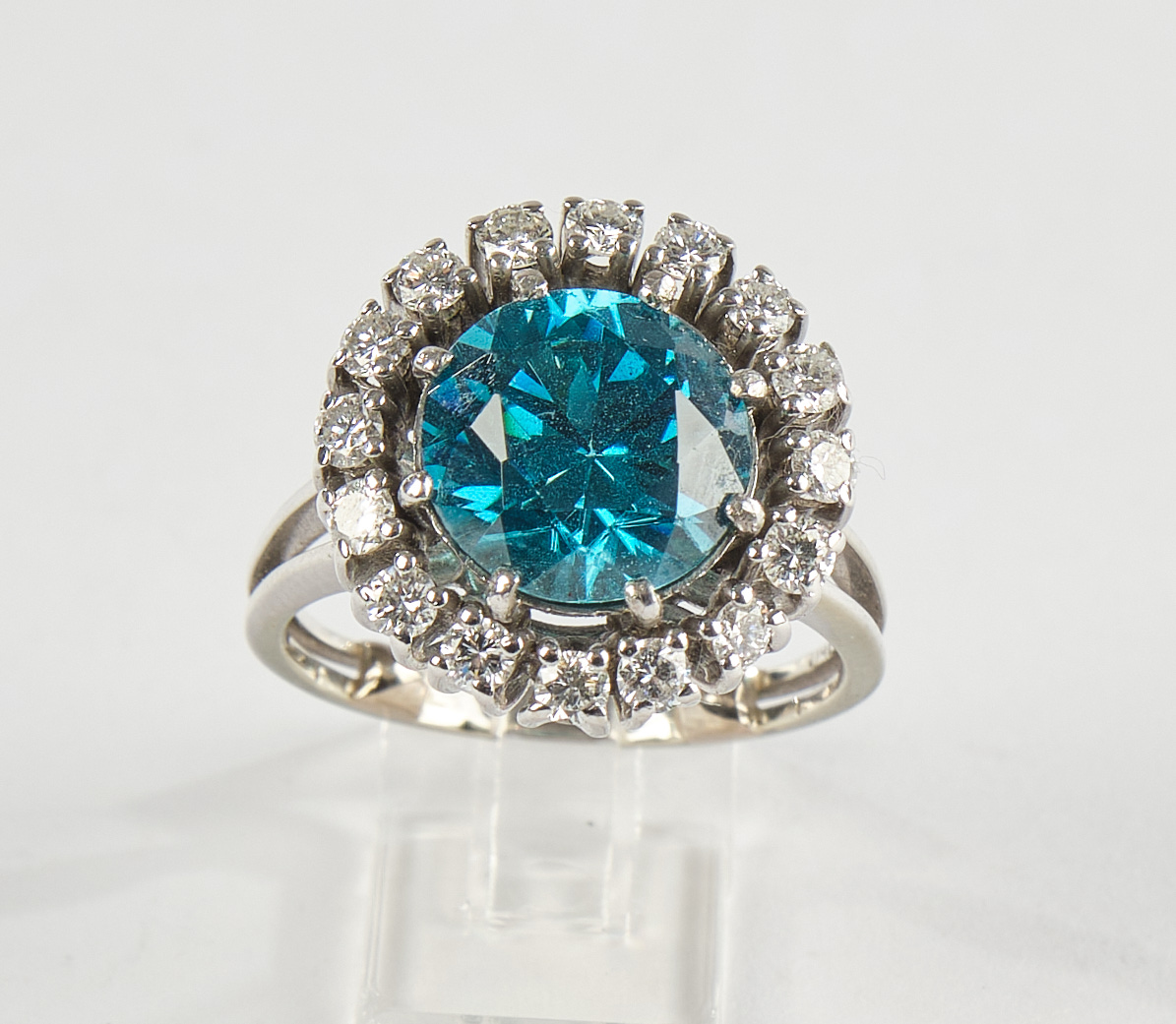 Farbsteinring, WG 750, um 1970, mit blauem Zirkon ca. 6 ct., 16 Brillanten je ca. 0.04 ct., zus. ca