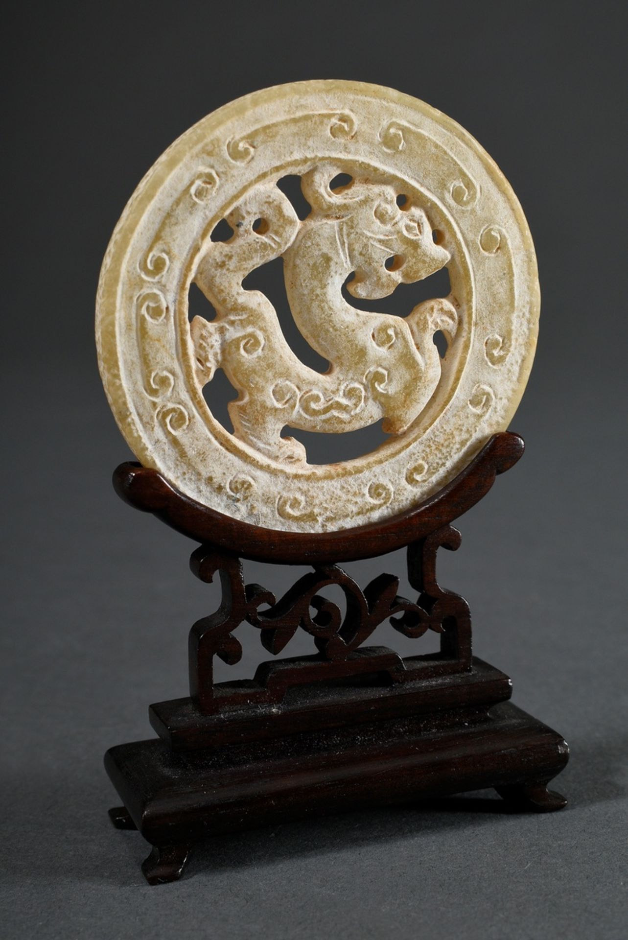 Huan jade disc with central mythical creature on a later Hongmu rosewood stand, surface mostly calc