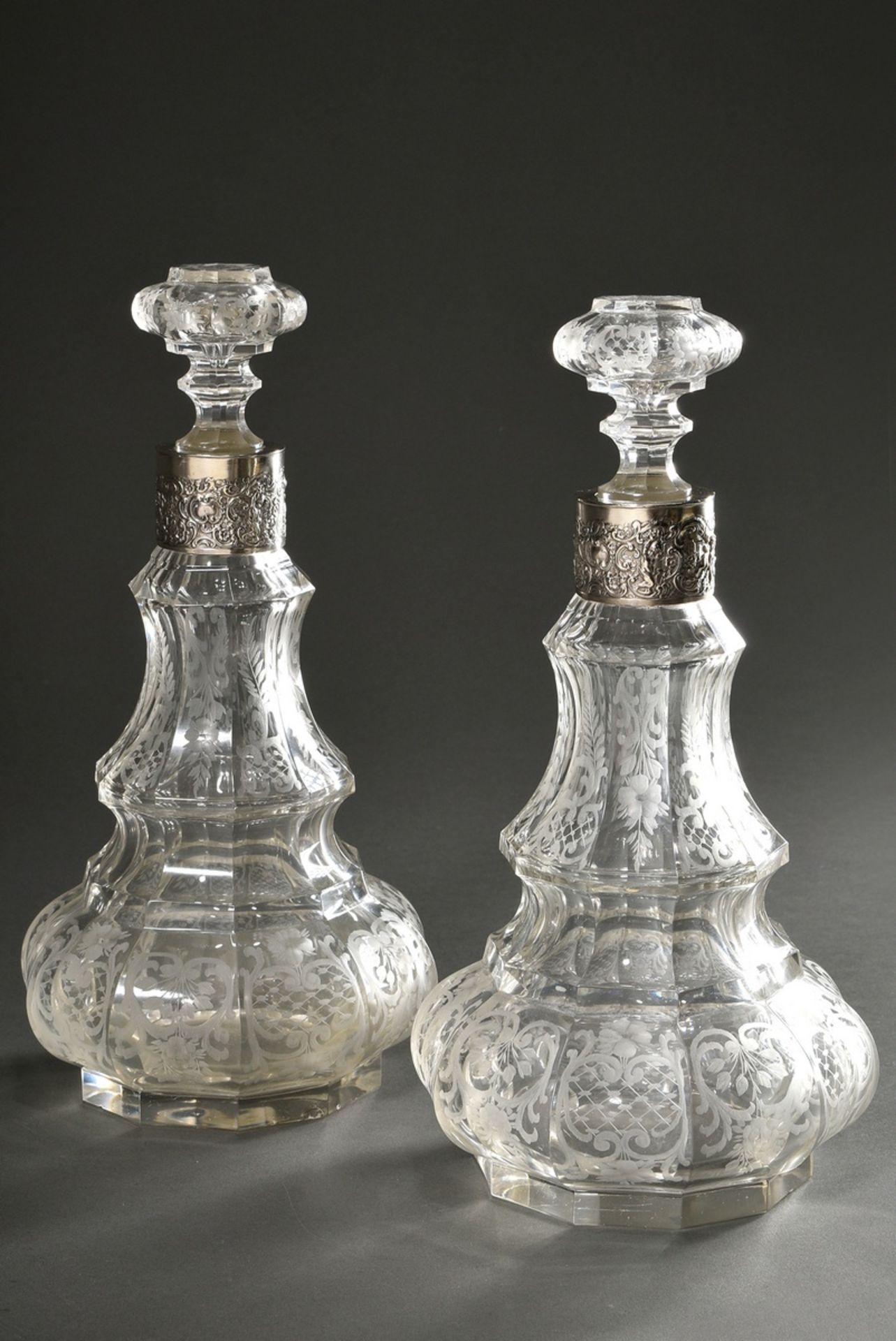 Pair of opulent crystal carafes in faceted baluster form with floral ornamental cut and silver 800 