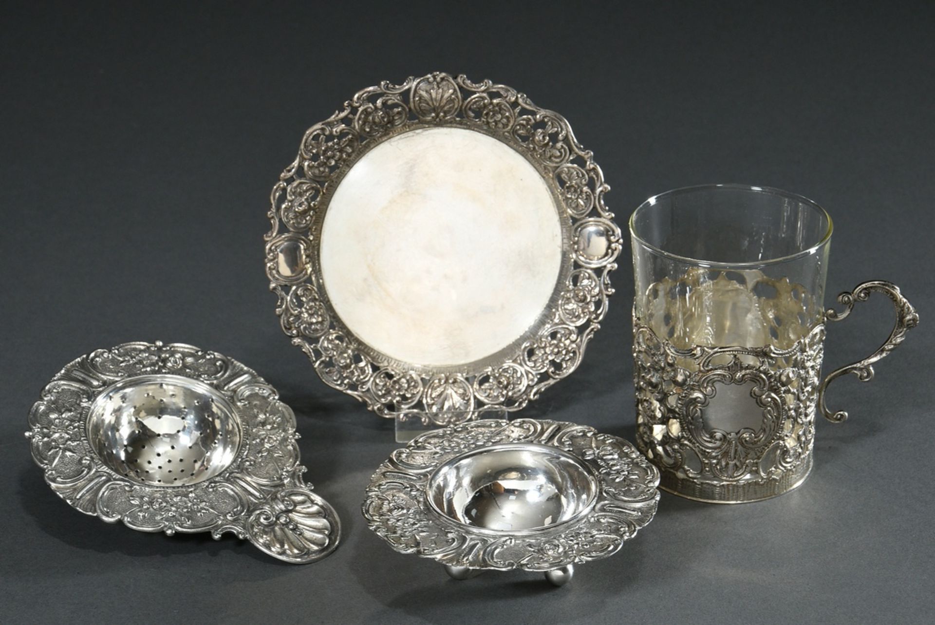 2 pieces richly reliefed tea glass on saucer and tea strainer on saucer "Roses and Rocailles", Germ