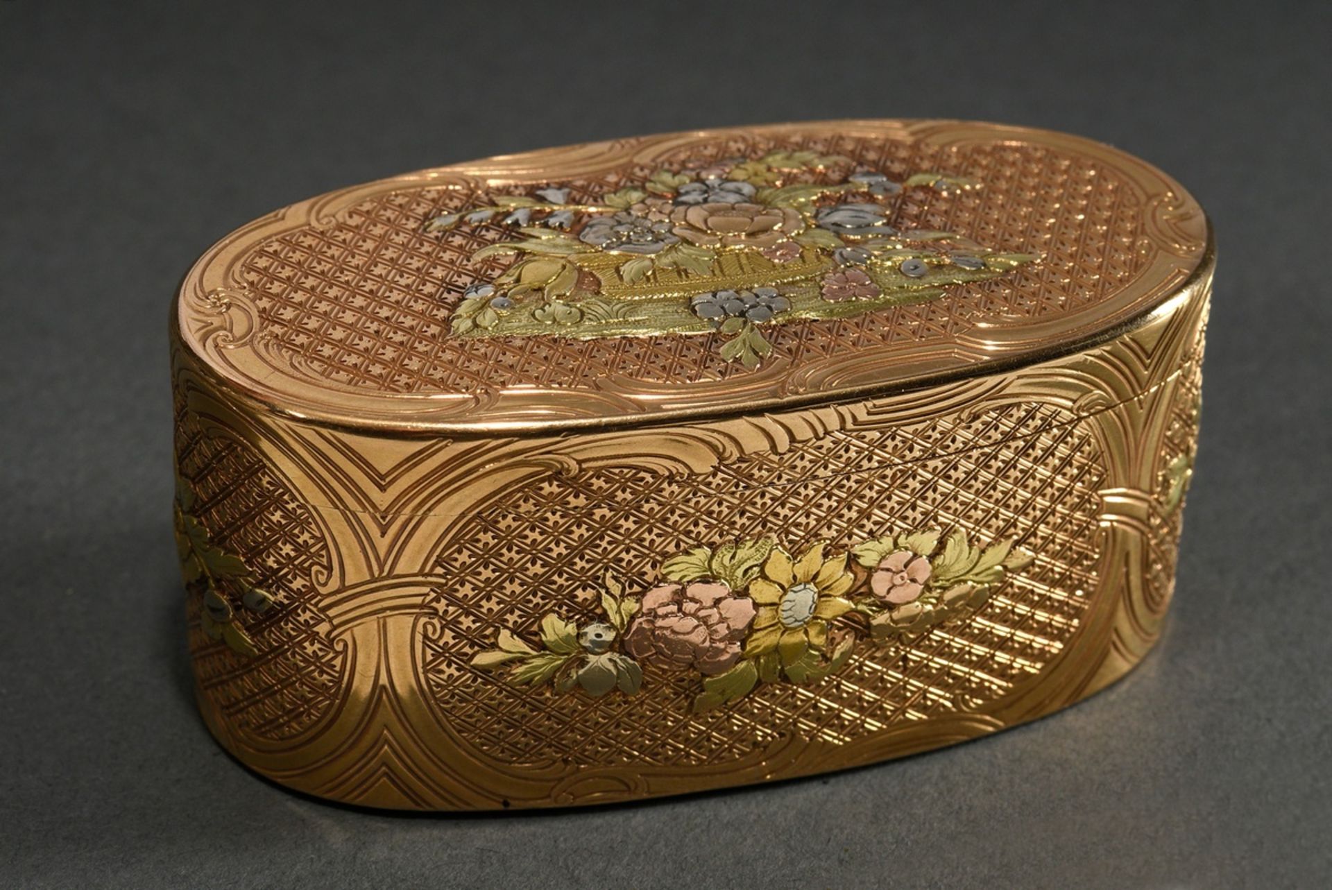 A very fine oval snuff box in tricolour gold, all sides geometrically chased with rocaille cartouch