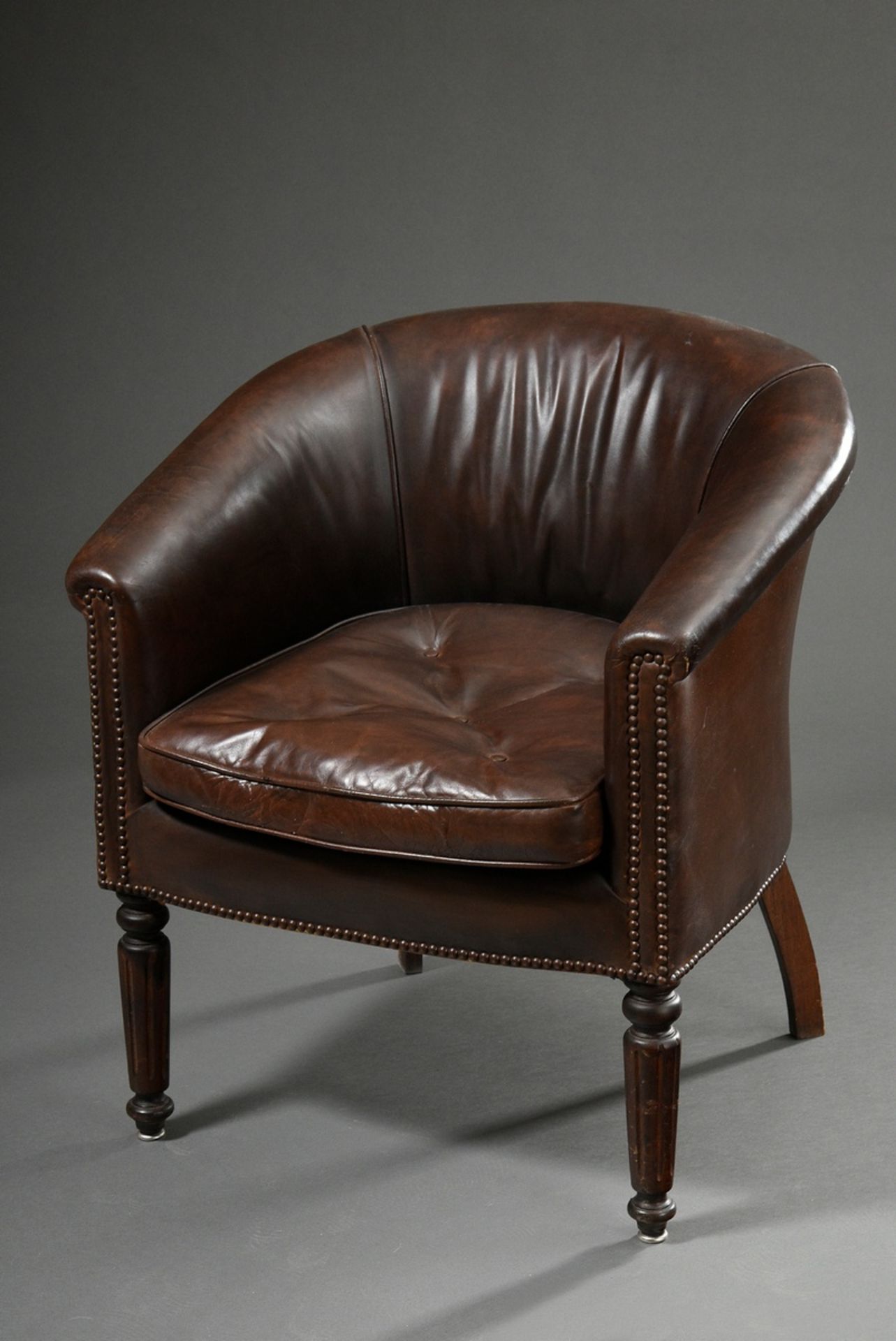 Dark brown leather club armchair with semi-circular backrest and fluted front legs, removable cushi
