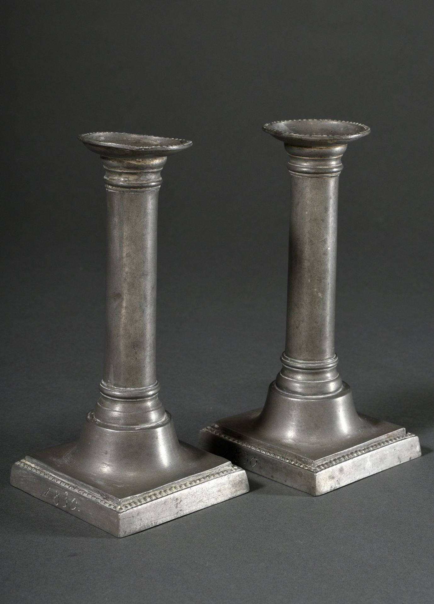 Pair of North German pewter candlesticks in column form on angular base with pearl frieze and engra