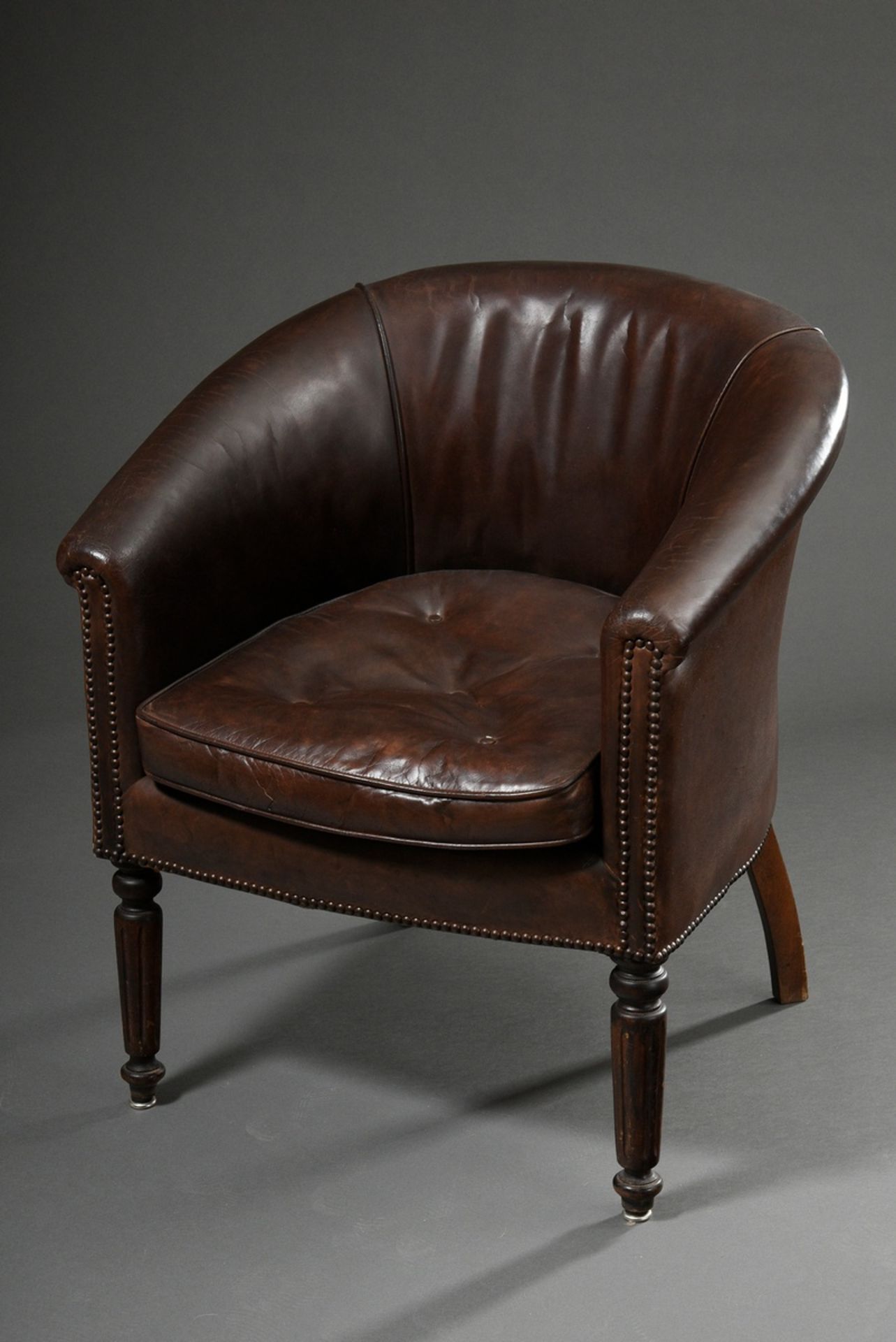 Dark brown leather club armchair with semi-circular backrest and fluted front legs, removable cushi