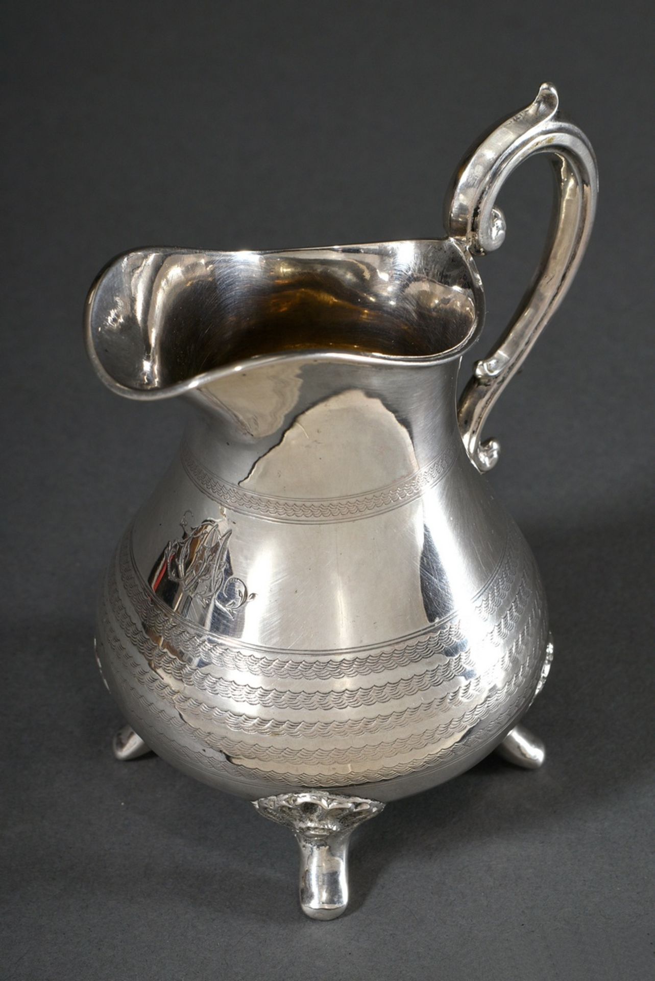 Cream jug on four shell feet with guilloché frieze, ligatured monogram engraving "CM" and curved ha