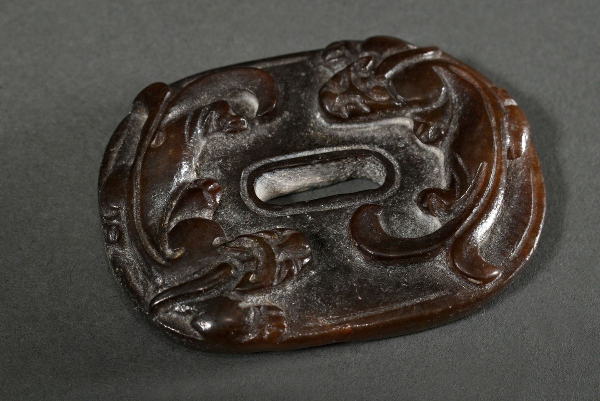 Oval dark brown jade in the shape of a Han period sword engraving with rain dragons and C ornaments