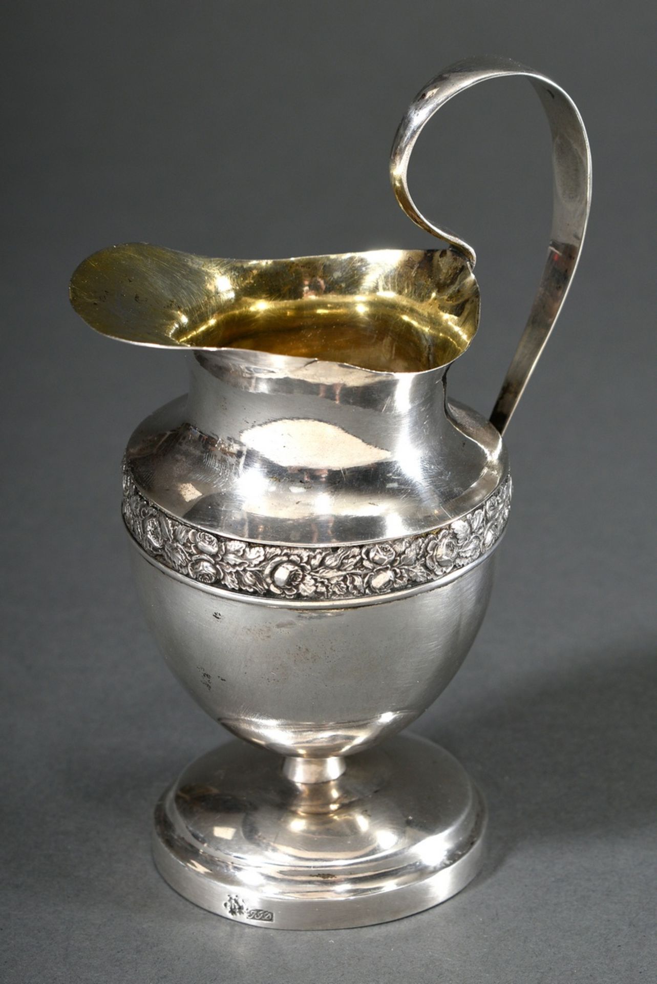 Cream pourer on a round foot with rose frieze in relief and raised handle with coat of arms in reli