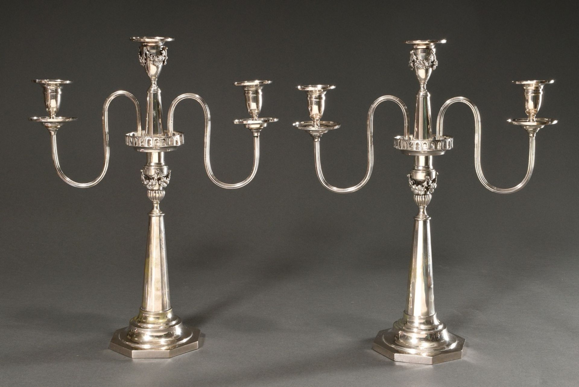 Pair of classicistic two-flame girandoles on an octagonal foot with conical faceted shaft and sculp