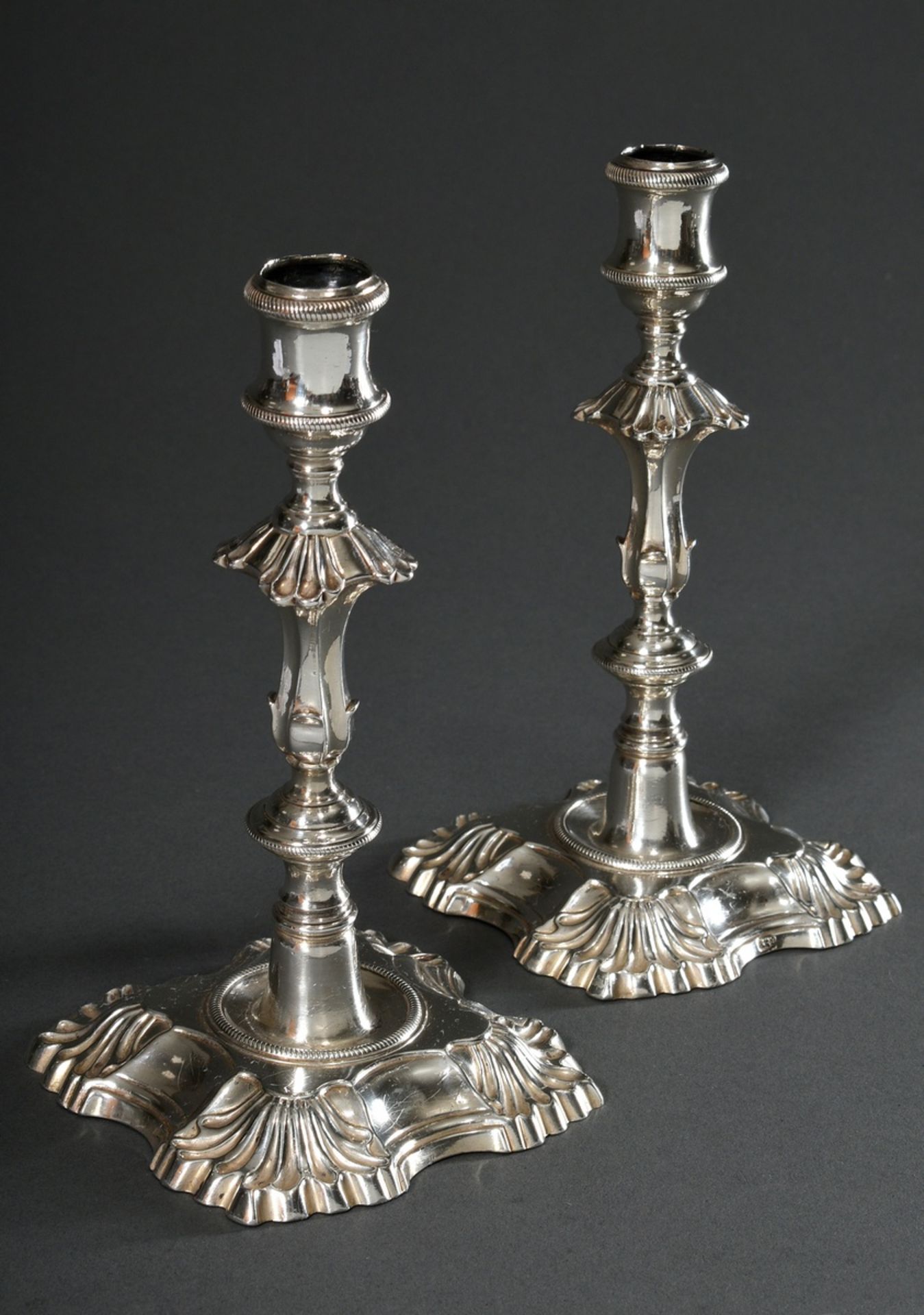 Pair of representative George II candlesticks on square footed base with indented sides and shell d