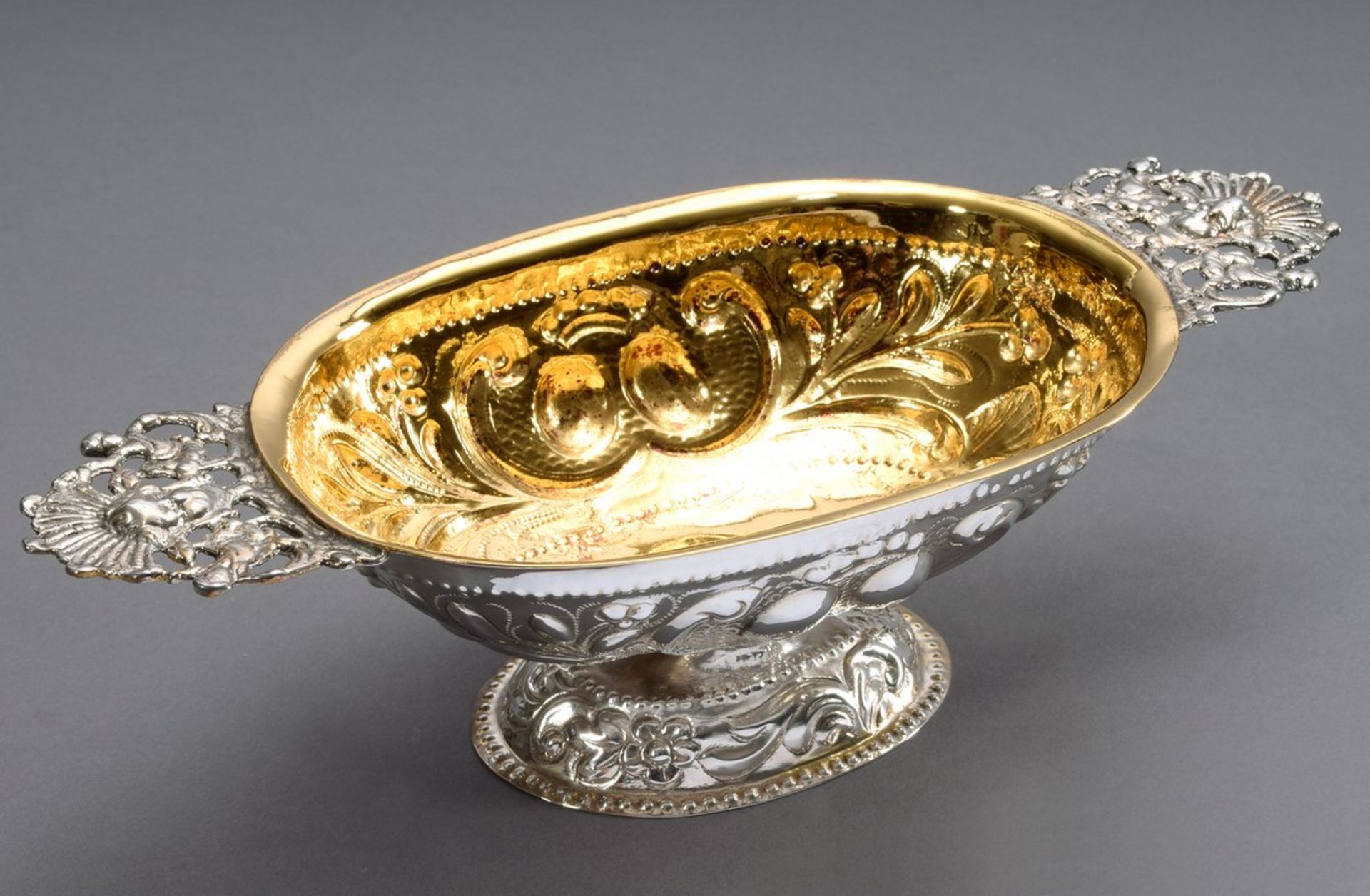 Oval brandy bowl with ornamental embossed wall and plastic handles with figural decoration, at the 