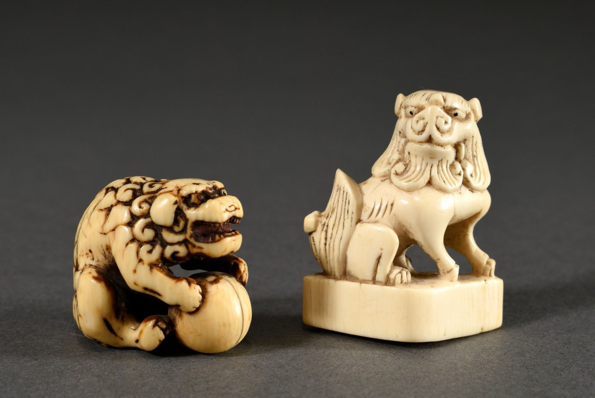 2 Various ivory netsukes "Shishi with ball" (h. 3cm, patina, crack) and "Sitting Shishi on base" (h