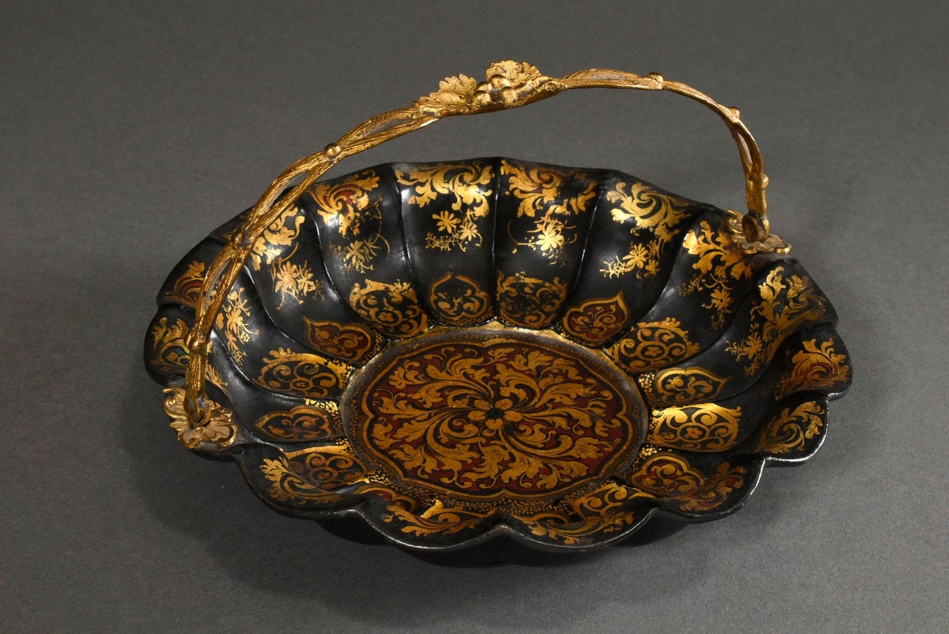 Flower-shaped papier-mâché bowl with a vegetal metal handle and floral gold painting on a red and g