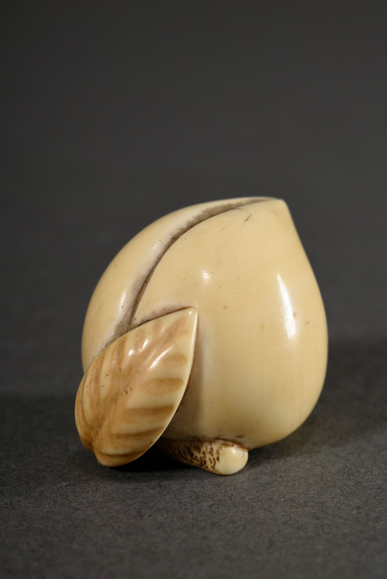 Ivory netsuke "Peach on branch with leaf", in cartouche sign. 蘭一 Ran'ichi, Japan 19th c., h. 2,4cm,