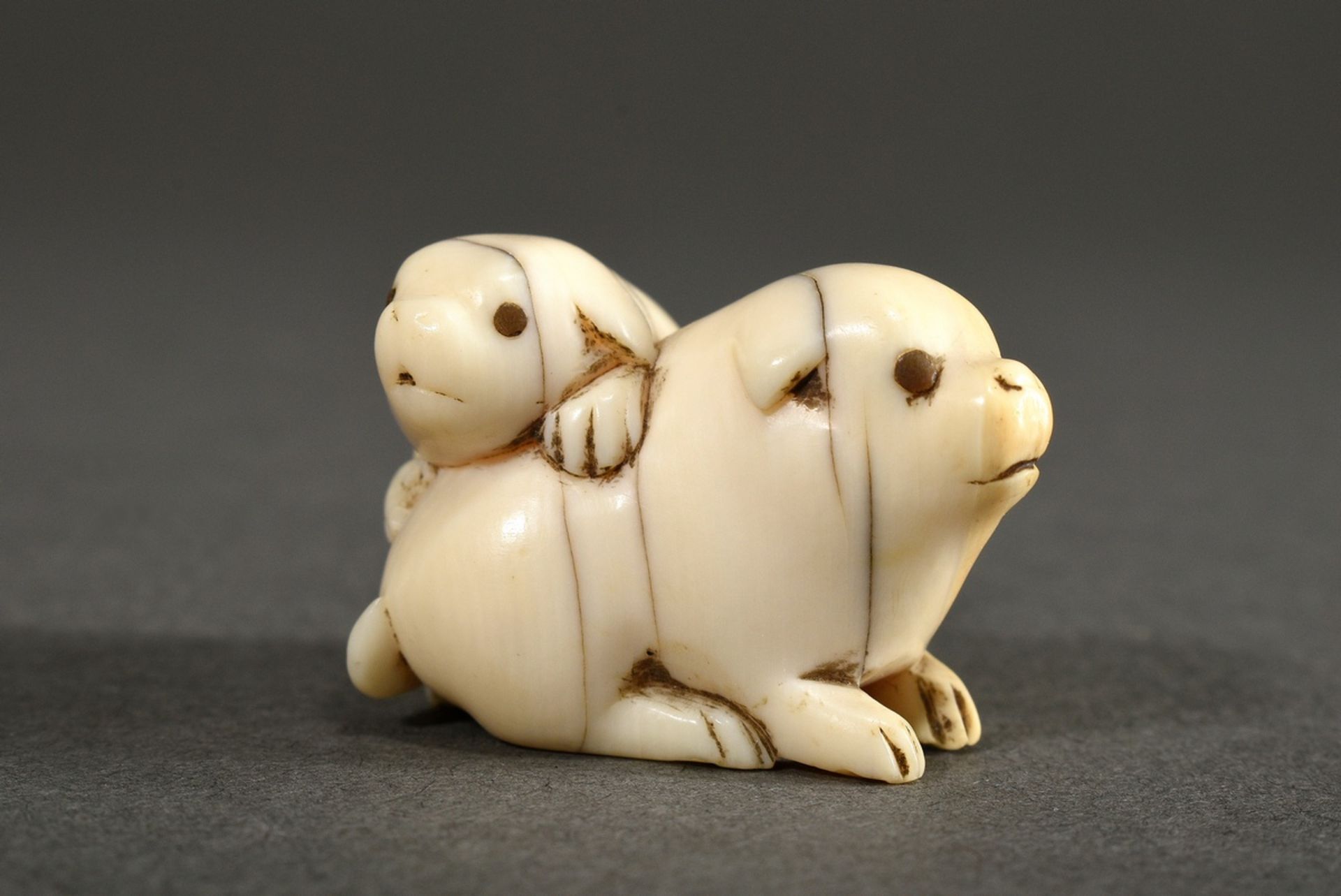 Ivory netsuke "Two puppies" with inlaid horn eyes (1 missing), Japan circa 1900, h. 2cm, cracks, ni