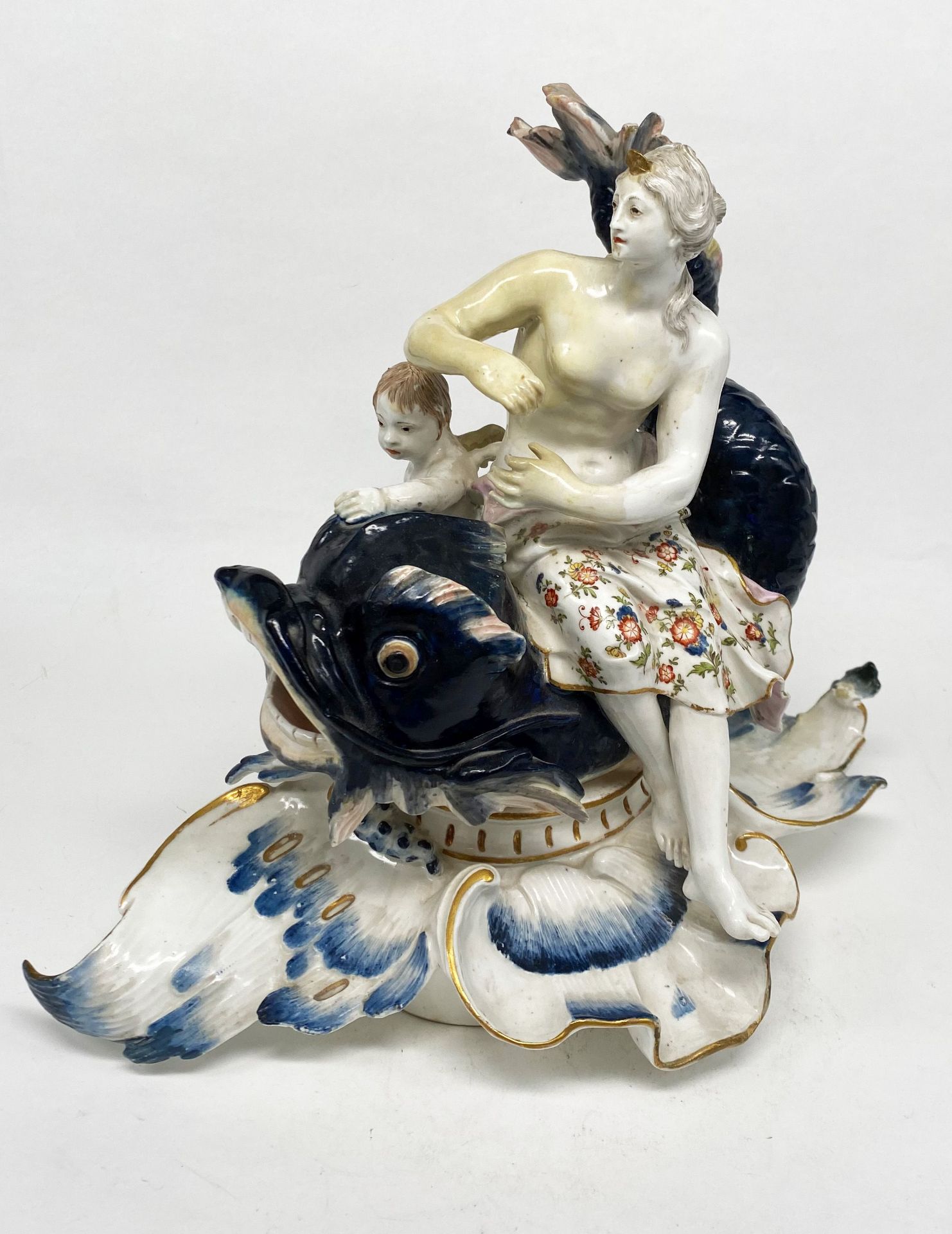 Porzellan-Figurengruppe Venus mit Amor auf Fisch sitzend, polychrom und gold staffiert, H. 25 cm;