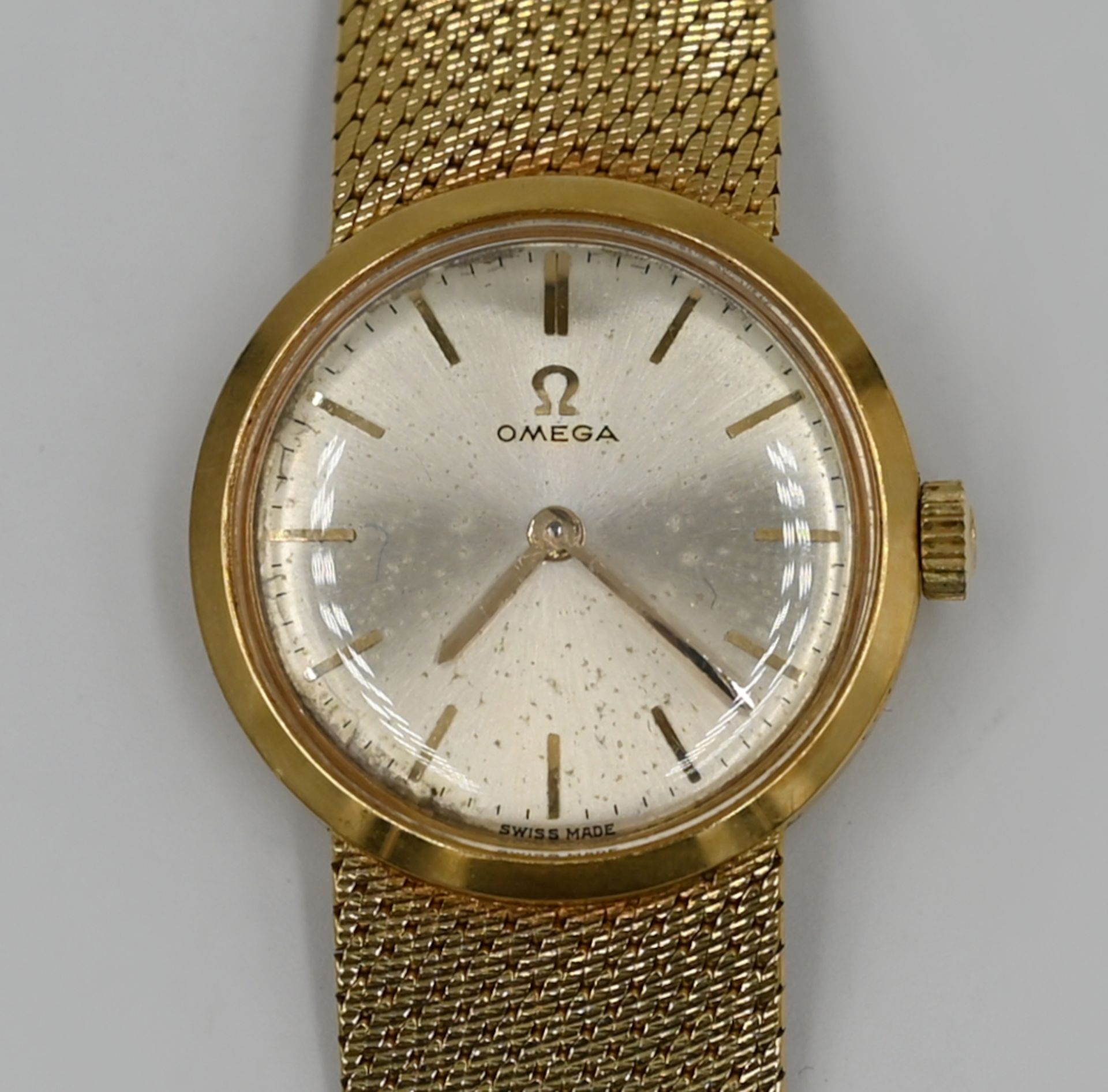 1 Damenarmbanduhr OMEGA, GG 18ct., in Originalschatulle, fleckiges Ziffernblatt, Handaufzug, Uhr läu