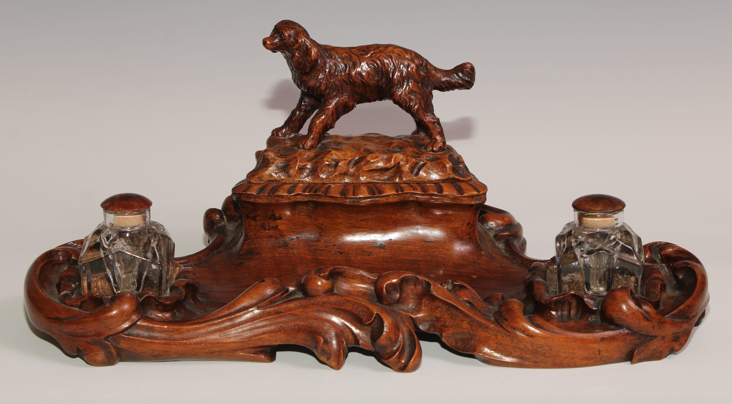 A 19th century walnut desk stand, carved in the Black Forest manner, the central compartment