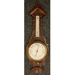 A carved oak barometer thermometer, floral carved case, cream aneroid scale, 89cm long