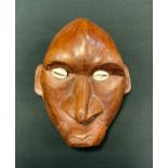An Oceania carved wooden maskhead, inset Cowrie shell eyes, 19.5cm high, 15.5cm wide