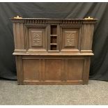 A 17th/18th century carved oak panel section, the top with central narrow three tier shelf between