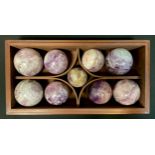 A set of Nine Amethyst and hard stone balls, various sizes, in mahogany case