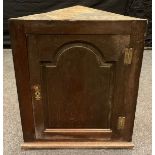 A 19th century wall hanging oak corner cabinet, single arched door, brass H hinges, 89cm high,