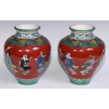 A pair of Japanese ovoid vases, painted in polychrome with figures on a cinnabar ground, 26cm