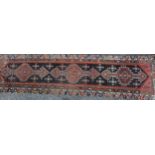 A Middle Eastern wool runner rug, rectangular field worked with hooked medallions, banded borders