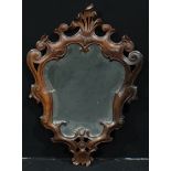 A 19th century Continental walnut cartouche shaped looking glass, beveled mirror plate, the border