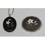 An Ashford black marble pietra dura oval brooch, with crisp white flower and foliage, silver