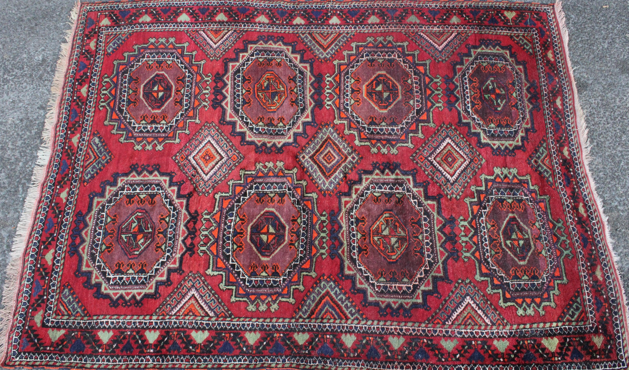 A Middle Eastern rectangular wool rug or carpet, the field worked with hooked medallions and