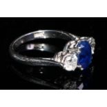 A three stone diamond, sapphire and 18ct gold ring, the central oval sapphire flanked by a pair of