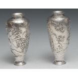 A pair of Japanese silver ovoid vases, chased with birds and blossoming prunus, on a textured