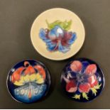 A Moorcroft Hibiscus pattern dish, tube lined with blue flowerhead on an ivory ground, 14cm diam,