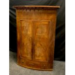 A 19th century mahogany bow front corner cabinet, the frieze with spindles, drawers to base, 124cm