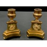 A pair of post-Regency bronze candlesticks, canted incurved bases applied with roses, bun feet, 11.