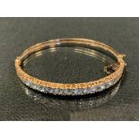 An Edwardian diamond and aquamarine hinge bangle, inset with eleven old round cut aquamarines each