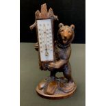A Black Forest desk thermometer, the rectangular scale held by a standing bear, 31cm high, c.1900