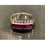 A ruby and diamond ring, set with six pinky red baguette cut rubies, between sixteen individually