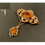 A Victorian citrine and gilt metal metal pendant brooch, scrolling body and pendant droplet set with